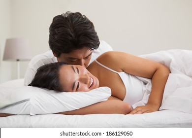 Couple lying in bed and cuddling at home in bedroom