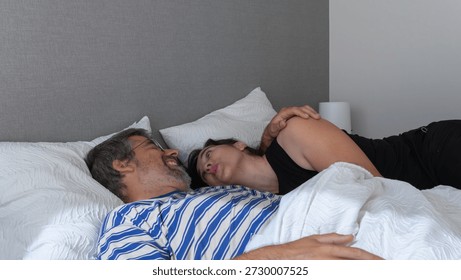Couple lying in bed looking at each other, sharing a tender and intimate moment, expressing love and connection
