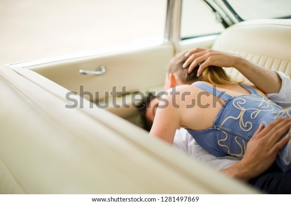 Couple lying down in back\
seat of car