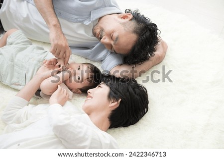 A couple lying down in the living room with their baby Overhead view
