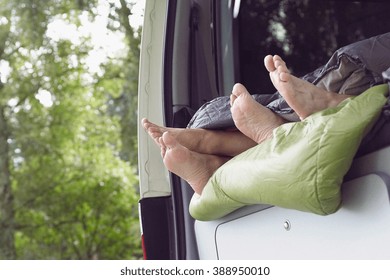 Couple lying inside open camper van, focus on feet