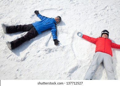 Couple Lying On Snow Making Snow Angel