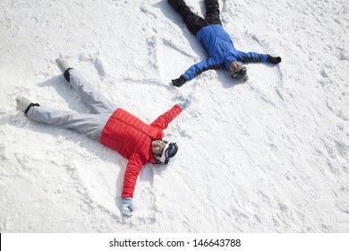 Couple Lying On Snow Making Snow Angel