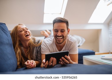 Couple lying on a sofa and using the tablet. - Powered by Shutterstock