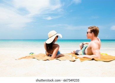 Couple lying on white sand beach relaxing and taking a sunbath in summer - Powered by Shutterstock