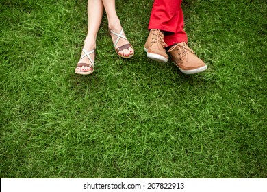 Couple lying and relaxing on the grass. Legs, top view, text space.