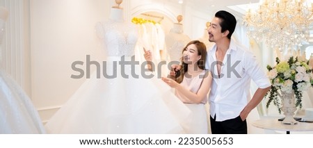 A couple makes inquiries about wedding gowns while at a wedding studio to choose the wedding dresses.