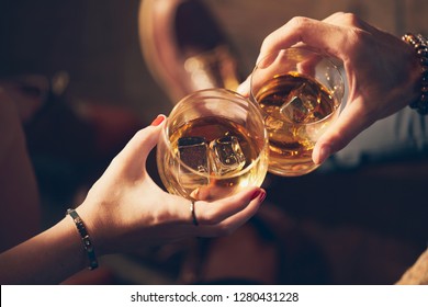 A couple makes a toast with two glasses of whiskey - Powered by Shutterstock
