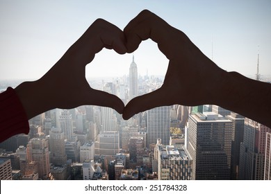 Couple making heart shape with hands against new york