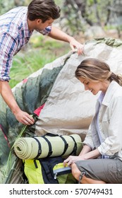 Couple making tent while camping in forest