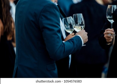 Couple of man  with a glass of wine at social event wearing elegant cloth.