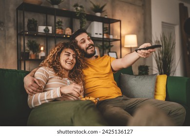 Couple man and woman caucasian husband and wife or boyfriend and girlfriend sit on the sofa bed at home watch tv movie series with hold remote controller happy smile bonding love family concept - Powered by Shutterstock