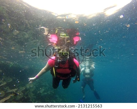 Couple of man and woman dive underwater with the oxygen tank equipment, vest, snorkel, fins, regulator enjoy the sport activity
