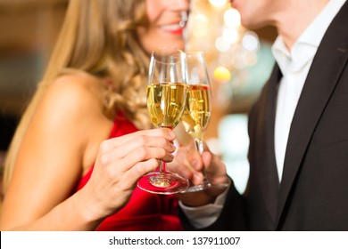 Couple, Man And Woman, Drinking Champagne In A Fine Dining Restaurant, Each With Glass Of Sparkling Wine In Hand