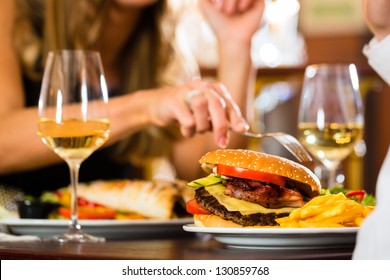 Couple - Man And Woman - In A Fine Dining Restaurant They Eat Fast Food, Burger And Fries, Closeup