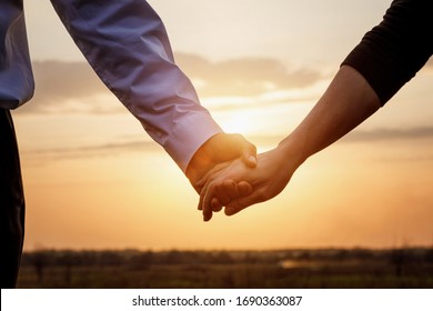 Couple man and woman hold hands on sunset background. - Powered by Shutterstock