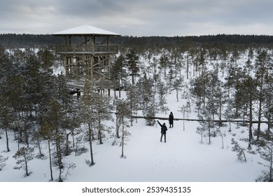 A couple, a man and a woman, on a winter day in the Viru swamp near a wooden observation tower. Everything around is in snow. - Powered by Shutterstock