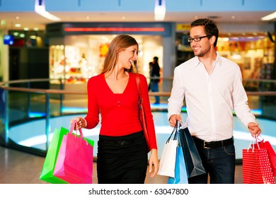 Couple - Man And Woman - In A Shopping Mall With Colorful Bags Simply Having Fun