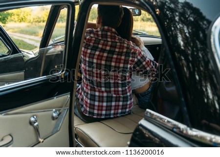 couple, man and woman are sitting in the car, the guy is hugging the girl. traveling together. check shirt and white blouse, darkies