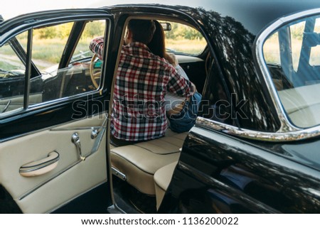 couple, man and woman are sitting in the car, the guy is hugging the girl. traveling together. check shirt and white blouse, darkies