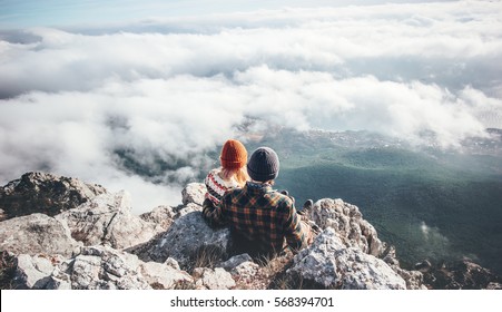 Couple Man and Woman sitting on cliff enjoying mountains and clouds landscape Love and Travel happy emotions Lifestyle concept. Young family traveling active adventure vacations