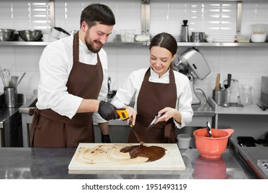 Couple, A Man And A Woman Temper The Chocolate And Measure The Temperature With A Non-contact Thermometer.