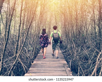 Couple man and woman walking together to Old wooden bridge surrounding with mangrove trees forest, copy space , go to target success, natural travel concept - Powered by Shutterstock