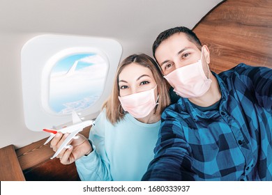 A Couple Of Man And Woman Wearing Medical Masks And Respirators Travel In The First Class Of An Airplane During An Outbreak Of The Coronavirus And Flu Pandemic