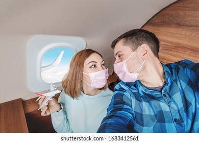 A Couple Of Man And Woman Wearing Medical Masks And Respirators Travel In The First Class Of An Airplane During An Outbreak Of The Coronavirus And Flu Pandemic