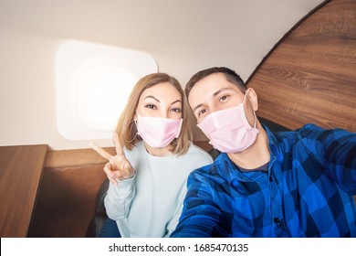 A Couple Of Man And Woman Wearing Medical Masks And Respirators Travel In The First Class Of An Airplane During An Outbreak Of The Coronavirus And Flu Pandemic