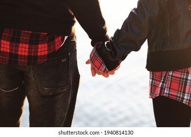 Couple In Matching Outfits Holding Hands In Front Of The Sea