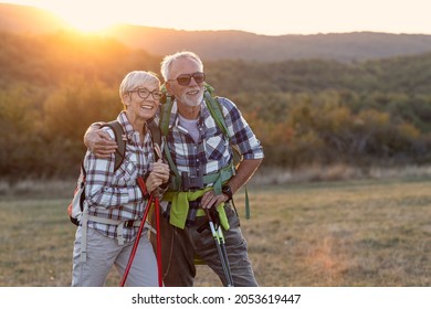 Couple of mature people smile and rest afther walking in nature with sunset on background - Powered by Shutterstock