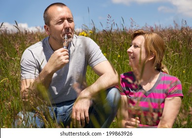 couple in a meadow with electric cigarette