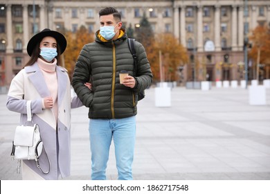 Couple in medical face masks walking outdoors. Personal protection during COVID-19 pandemic - Powered by Shutterstock