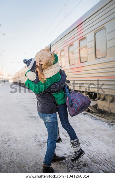 Couple meet each other after long time at\
railway station near train in a cold winter\
day