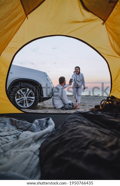 couple meeting sunrise at sea beach. view\
through camping tent. summer\
vacation