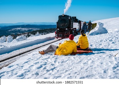 couple men and woman hiking in the Harz national park Germany, Steam train on the way to Brocken through the winter landscape, Famous steam train through the winter mountain. Brocken, Harz Germany - Powered by Shutterstock