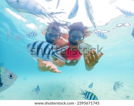 A couple of men and a woman on a snorkeling trip at Samaesan Thailand. dive underwater with Nemo fishes in the coral reef sea pool. couple swim activity on a summer beach holiday 