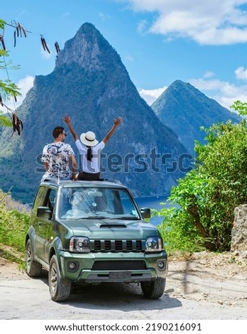 a couple of men and women exploring the Island of St Lucia in a rental car. Mountains of Saint Lucia with in the background the huge pitons in the ocean with palm trees