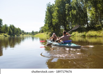 A couple of men and women kayak on the river in the summer. Active recreation, family travel, extreme adventure, sports and ecological domestic tourism. Equipment for rafting, boat, oars.