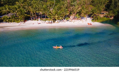 A Couple Of Men And Women Are Kayaking In The Rainforest Of Koh Chang Thailand Tropical Island. Drone View From Above At The Rainforest With Couple In Kayak At Tropical White Beach With Palm Trees