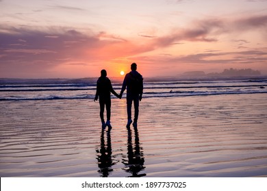 couple of men and women mid-age watching the sunset on the beach of Tofino Vancouver Island Canada, beautiful sunset on the beach with pink-purple colors in the sky. Canada Tofino
