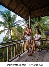 A Couple Of Men And Women On The Balcony Of A Beach Hut With Coffee In Railay Beach Krabi Thailand In The Morning, Men And Woman Waking Up In A Backpacker Hut In Thailand