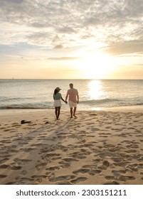 A couple of men and women are on the beach watching the sunset during vacation at Aruba Island Caribbean. man and woman by the ocean during susnet 