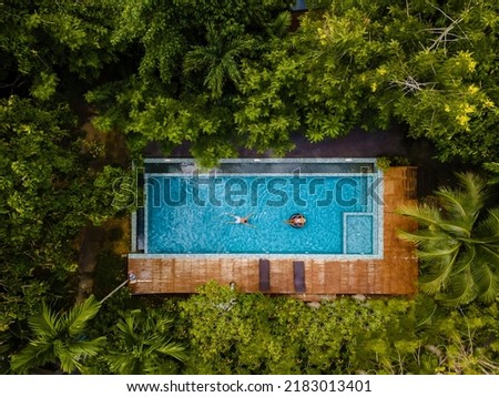 couple of men and women in a swimming pool in the jungle of Krabi Thailand, aerial view with a drone above swimming pool in the jungle of Thailand. 