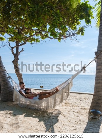 Couple of men and women watching the sunrise in a hammock on a tropical beach in Hua Hin Thailand. Asian women and European men in a hammock on the beach of Huahin Thailand