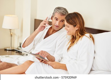 Couple With Menu Calling Room Service For Food From Hotel Room