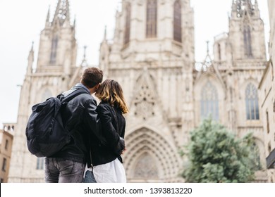 Couple Of Middle Age Enjoys Holidays In Barcelona. Back View Of A Young Pretty Stylish Couple On Vacations In Barcelona, Cathedral On Background. Space For Advertising Text. Inspirational Travel Image