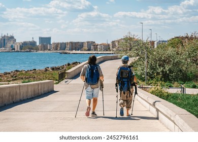 Couple of middle-aged women hiking together along path along beach, rear view - Powered by Shutterstock