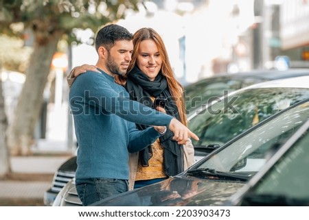 couple with mobile phone looking at cars to buy, buy car